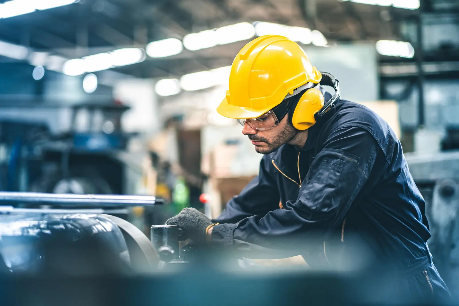 Trabalhador com capacete, óculos e proteção auditiva em ambiente industrial